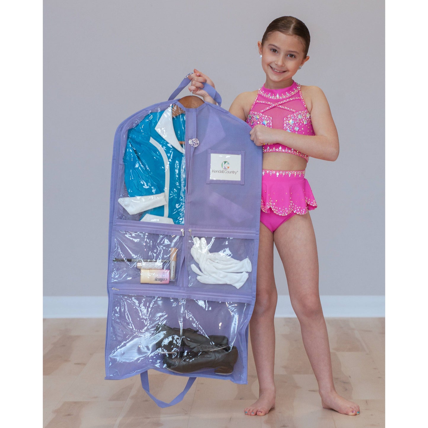 Dancer holding lavender coloured garment bag with clear pockets
