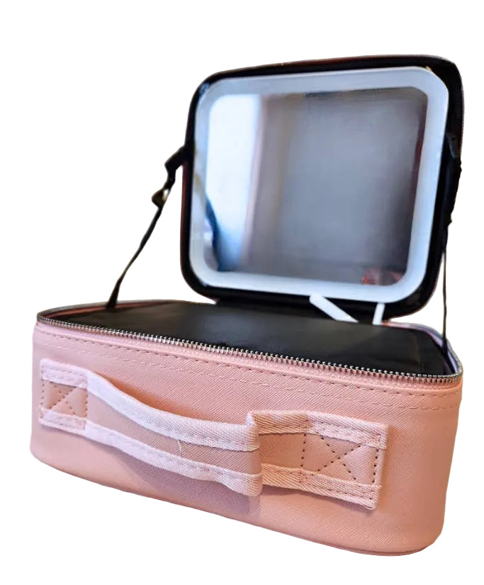 A light pink cosmetic case with an open mirror lid, resting on a beige quilted blanket background.