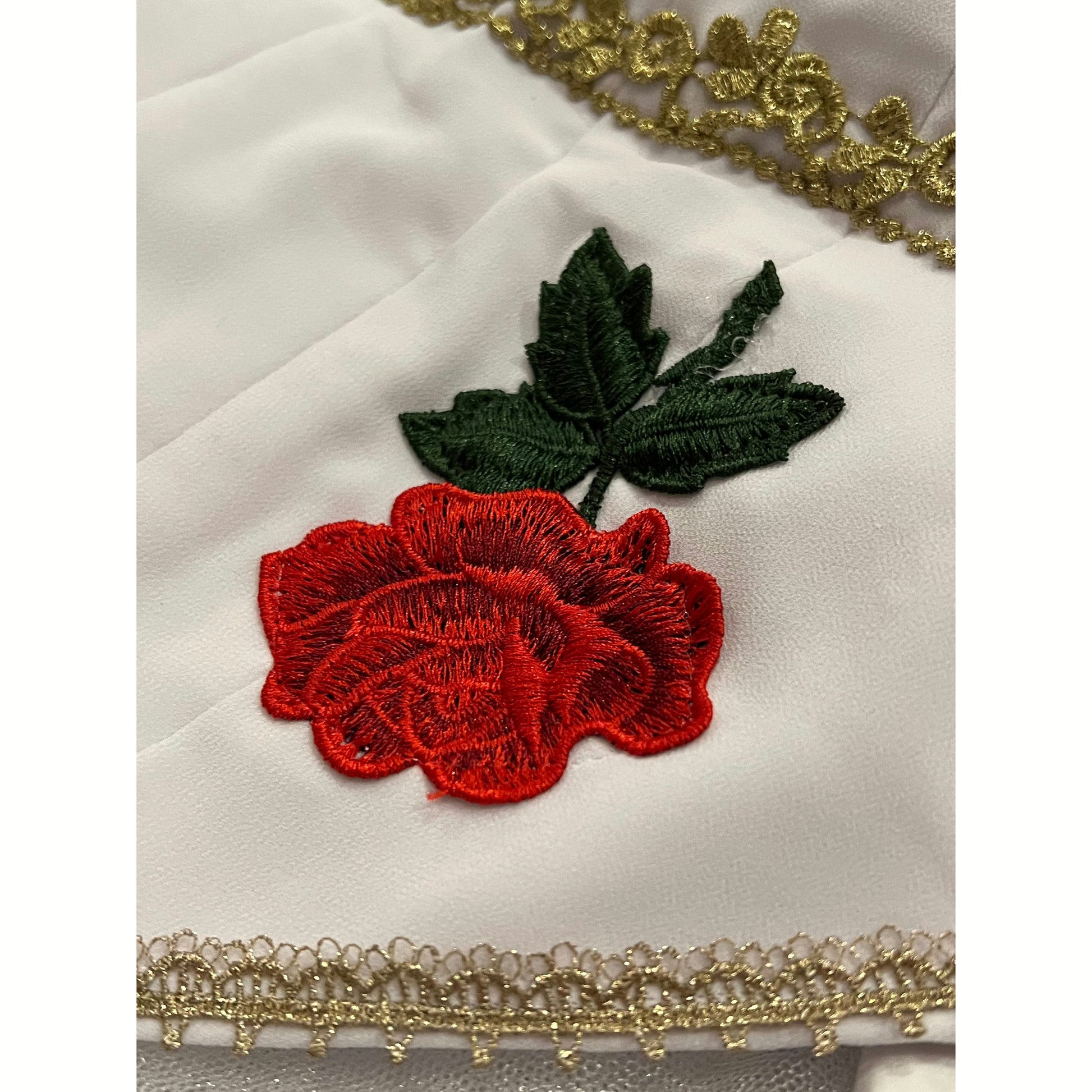 Close up of embroidered red rose and gold trim