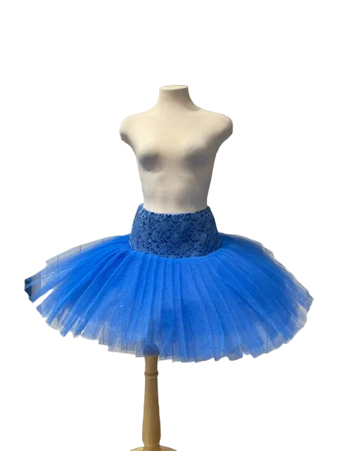 A bright blue tutu skirt with a textured blue lace waistband displayed on a white mannequin torso in a boutique setting.