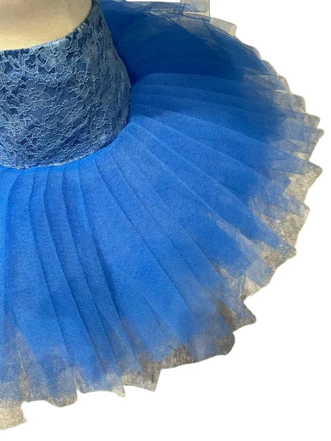 A bright blue lace tutu skirt with layered tulle, displayed on a mannequin against a gray-brown tiled floor.