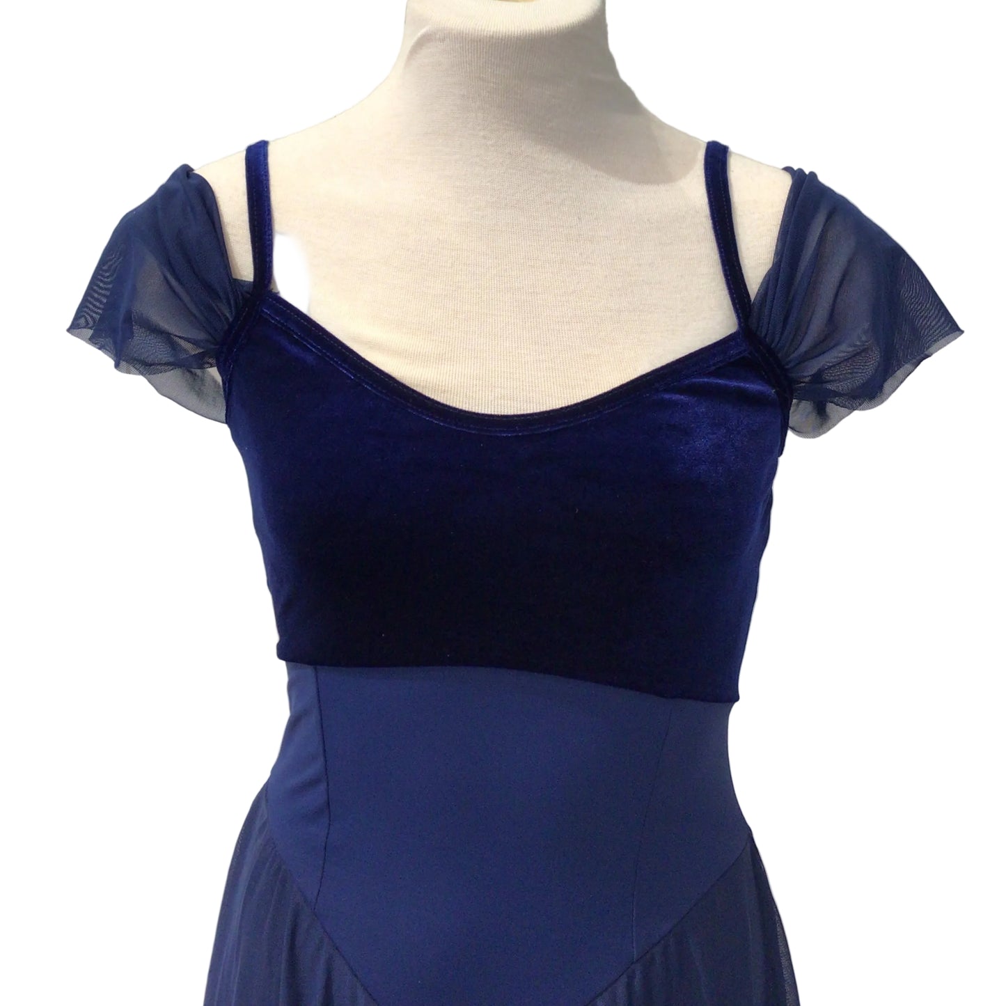 A royal blue dance dress displayed on a white mannequin torso against a white paneled wall. The dress features a velvet bodice with sheer flutter sleeves and a solid blue skirt.