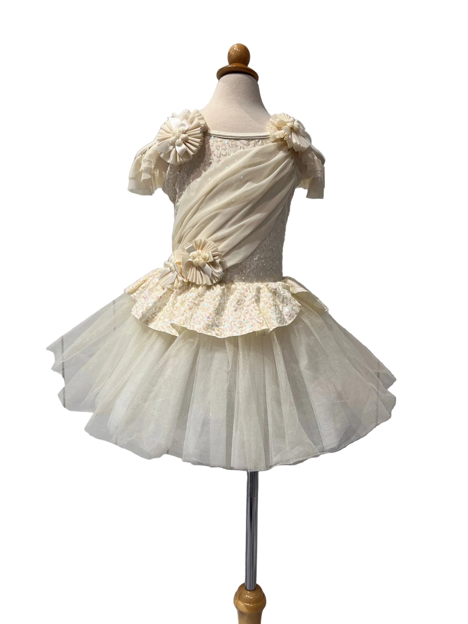 A cream-colored toddler girl's party dress displayed on a dress form mannequin. The dress features a draped off-the-shoulder bodice with floral appliques, a lace-embellished bodice, and a layered ruffled tulle tutu skirt.
