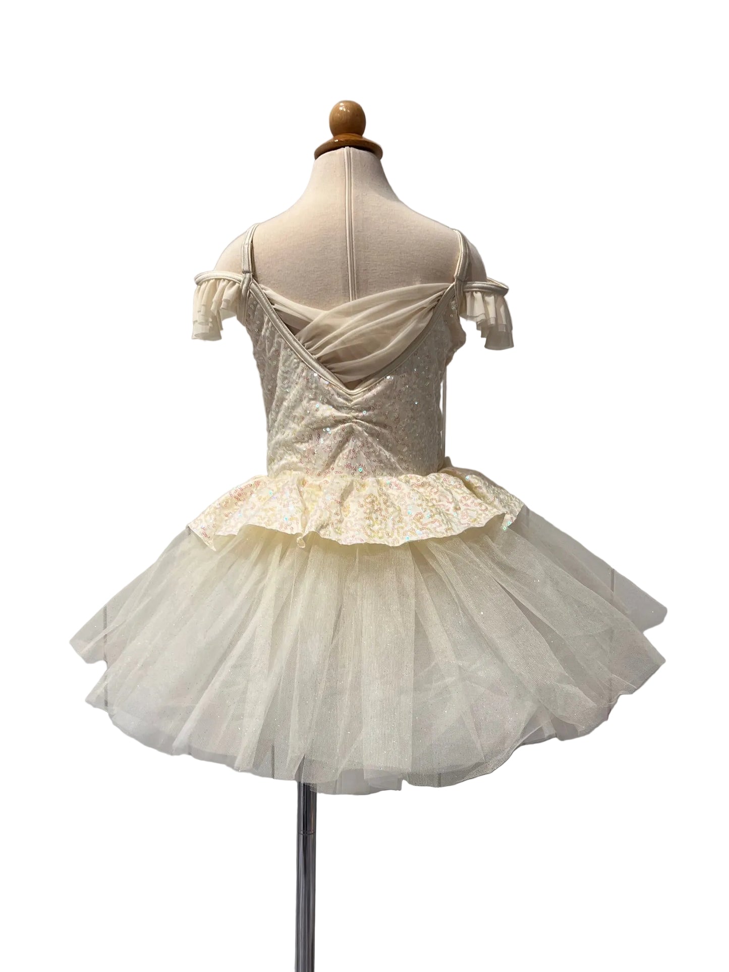 A cream-colored young ballerina costume dress displayed on a mannequin from the back. The dress features a sheer tulle tutu skirt, a ruffled waist, and a sequined off-the-shoulder bodice.