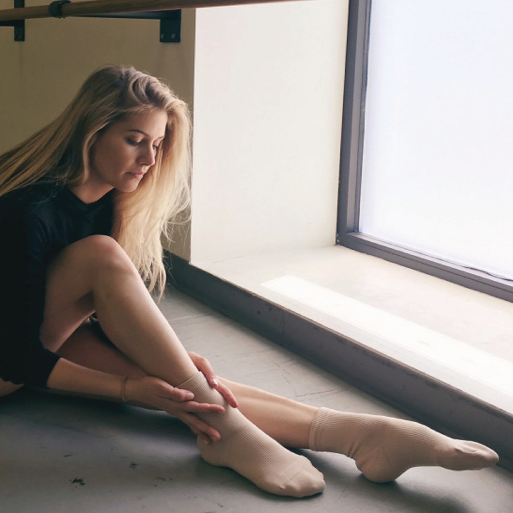 Dancer sitting down and wearing Apolla Performance Shock in nude