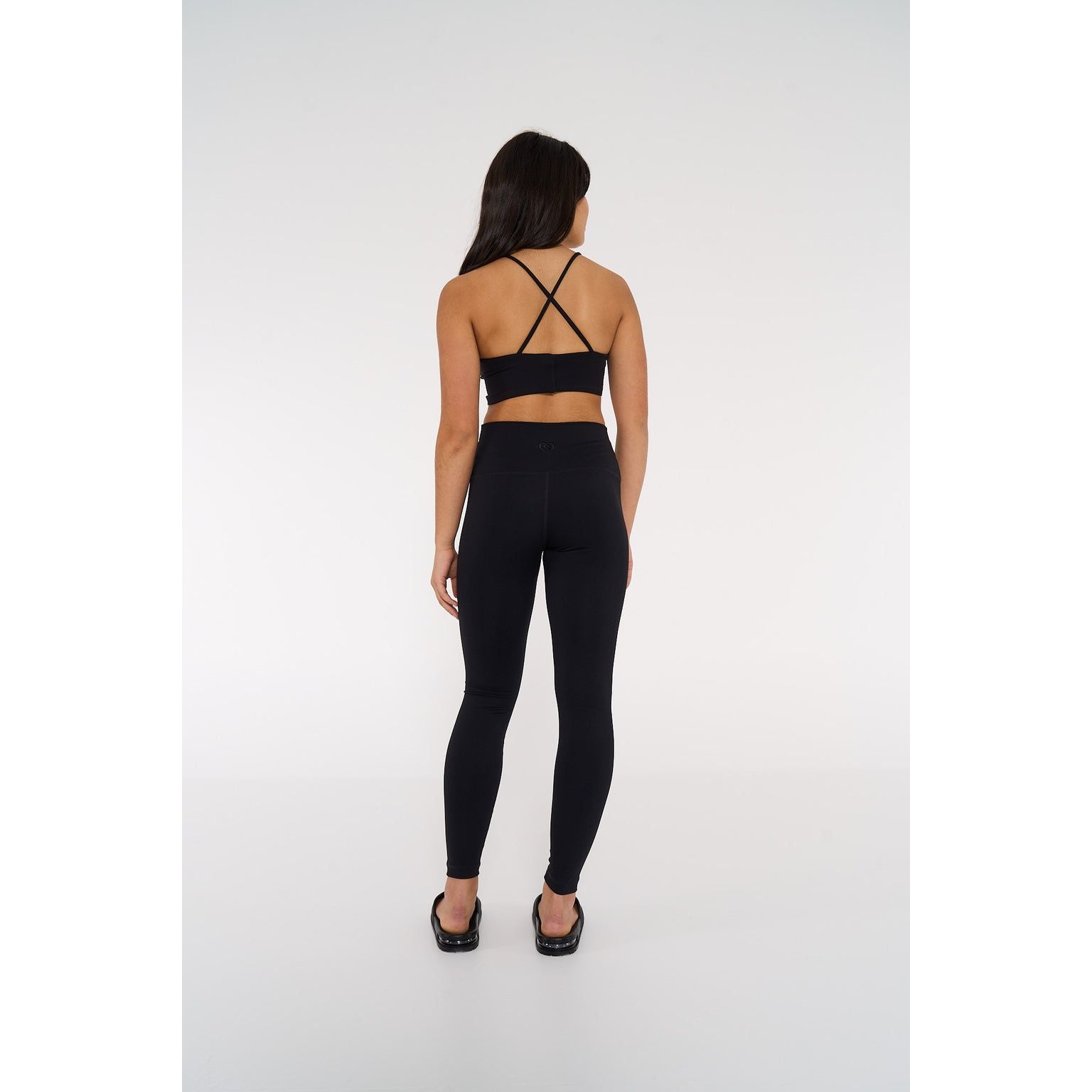 Dancer is wearing CDW high waisted leggings in black and showing us the back view