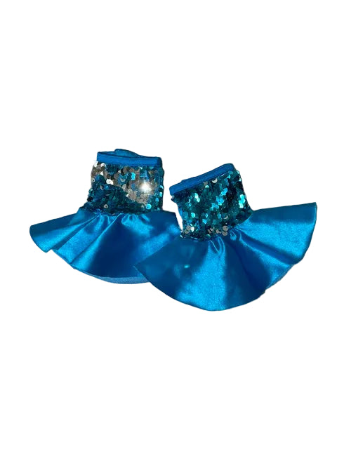 A pair of blue sequined and satin tutus with silver rhinestone trim, displayed flat on a gray wood-plank floor.
