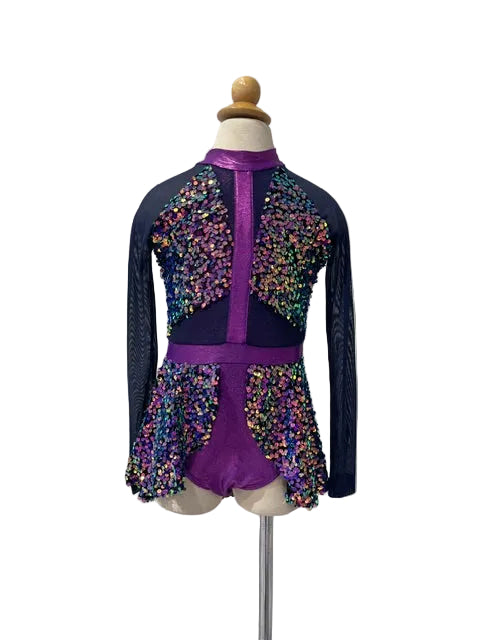 A purple and navy long-sleeve gymnastics or figure skating leotard with multicolor sequins, displayed on a mannequin torso against a white paneled wall.