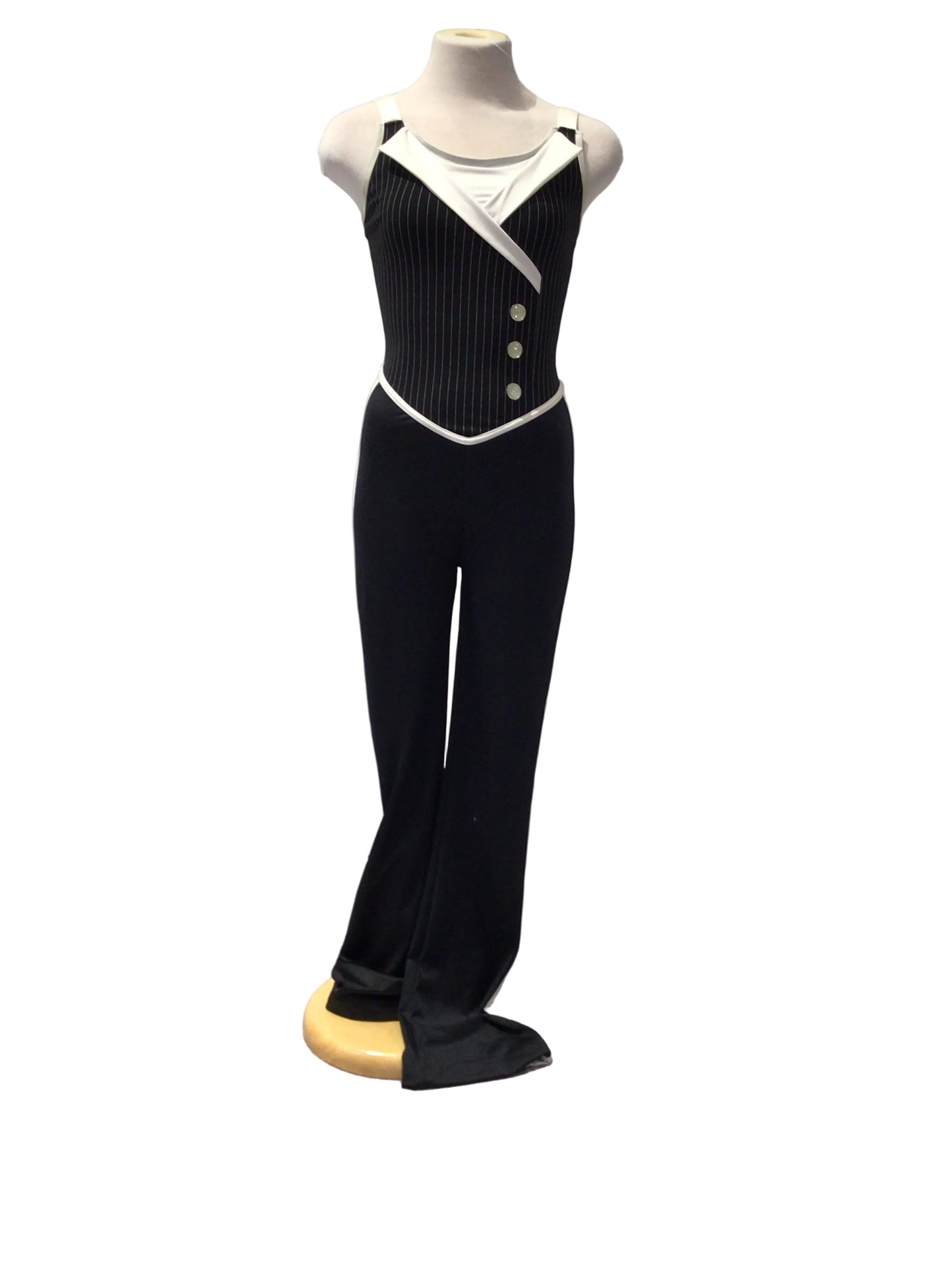 A black ribbed knit tuxedo-style costume displayed on a mannequin torso, featuring white trim, a white collar, and three decorative buttons on the chest, photographed indoors against a white paneled wall.