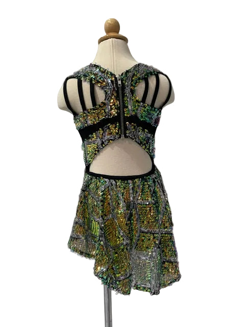 A sleeveless dance or performance dress displayed on a mannequin, featuring a black strappy cutout back bodice and a short asymmetrical skirt covered in iridescent sequins that shift between green, gold, and silver.