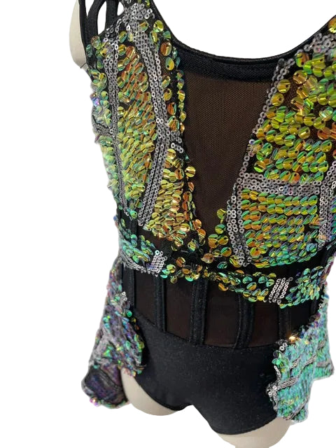 A close-up of a black dance or performance leotard with extensive iridescent sequin embellishments in green, blue, and gold, displayed on a mannequin torso.