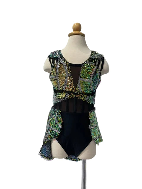 A sleeveless black leotard with elaborate green, gold, and silver sequined overlays, displayed on a cream mannequin torso against a white paneled wall.